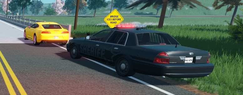 A sheriff patrol car behind a yellow coupe on a tree-lined road